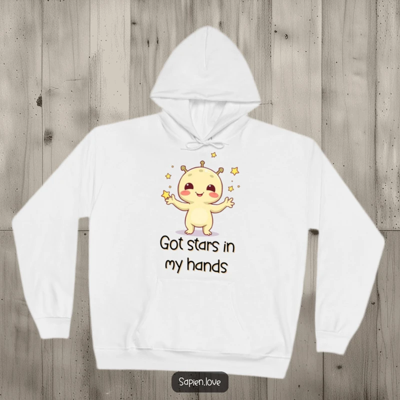 Funny hoodie featuring a cheerful alien creature enthusiastically juggling a constellation of tiny, sparkling stars.